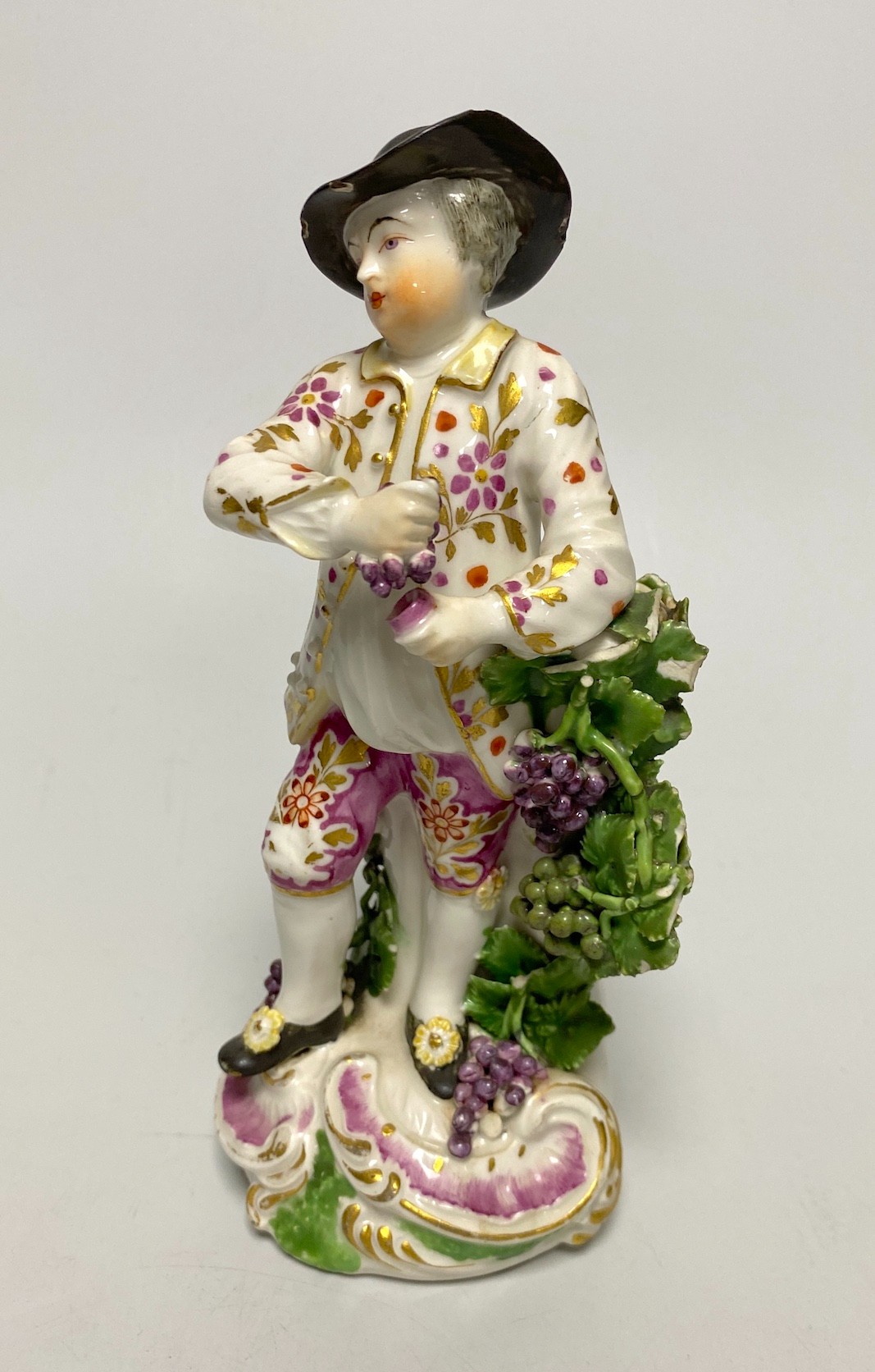 A Derby porcelain figure, emblematic of Autumn, modelled as a boy holding grapes and vine, 18th century, 18cm high